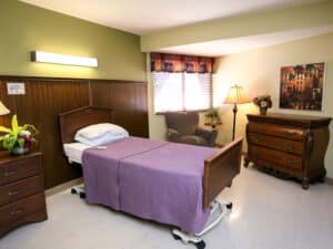 Single occupancy room with mahogany furniture and natural light streaming through the window.