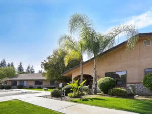 Front entrance with mature palm trees and a lush green lawn.