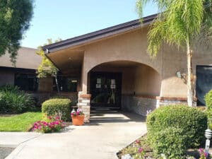 Bakersfield post acute covered arched entrance with mature trees and lots of greenery.