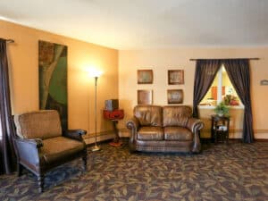 Waiting area with brown leather couch, leopard upholstered chair and a patterned carpet.